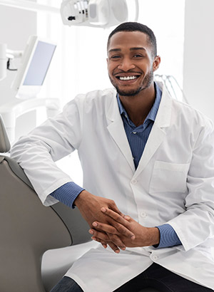 African American male dentist in treatment room smiling at camera