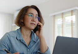 Woman sitting in front of computer while talking on phone