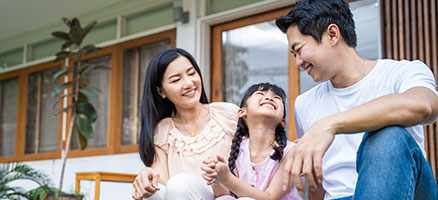 Family smiling and sitting on steps of house