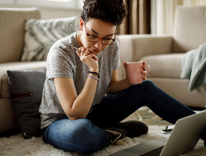 woman with coffee looking at laptop