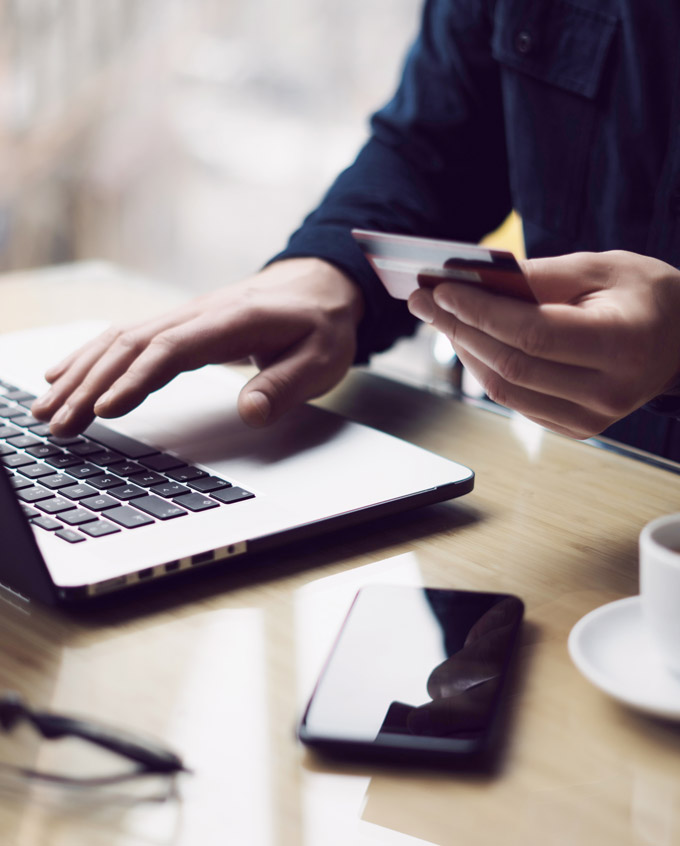 closeup of hands with credit card on a laptop