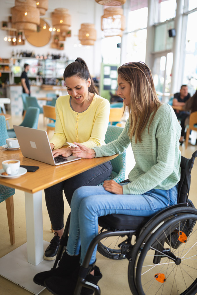 two female friends shopping online in a cafe