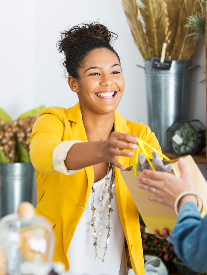 woman handing a customer a purchase at a store